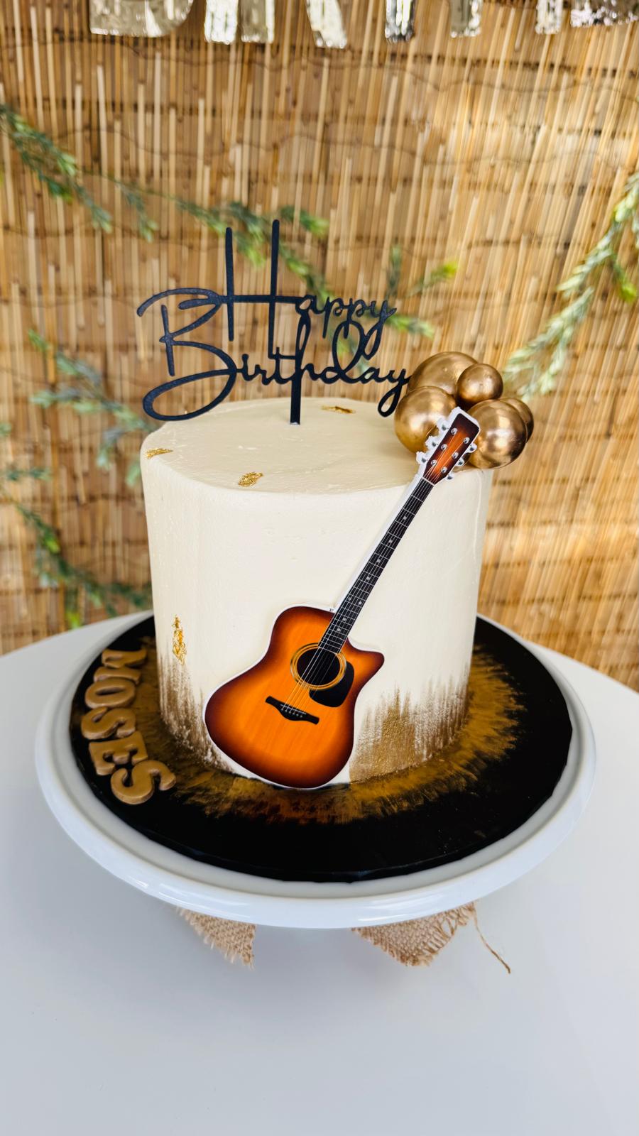 Birthday cake decorated with a miniature guitar and gold details